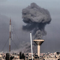 Cette photo, prise à Rafah, dans le sud de la bande de Gaza, donne à voir une colonne de fumée en train de s'élever au-dessus des bâtiments de Khan Younès lors d'un bombardement israélien, le 8 février 2024, alors que les combats se poursuivent entre Israël et le groupe terroriste palestinien Hamas. (Crédit : Mahmud Hams/AFP)