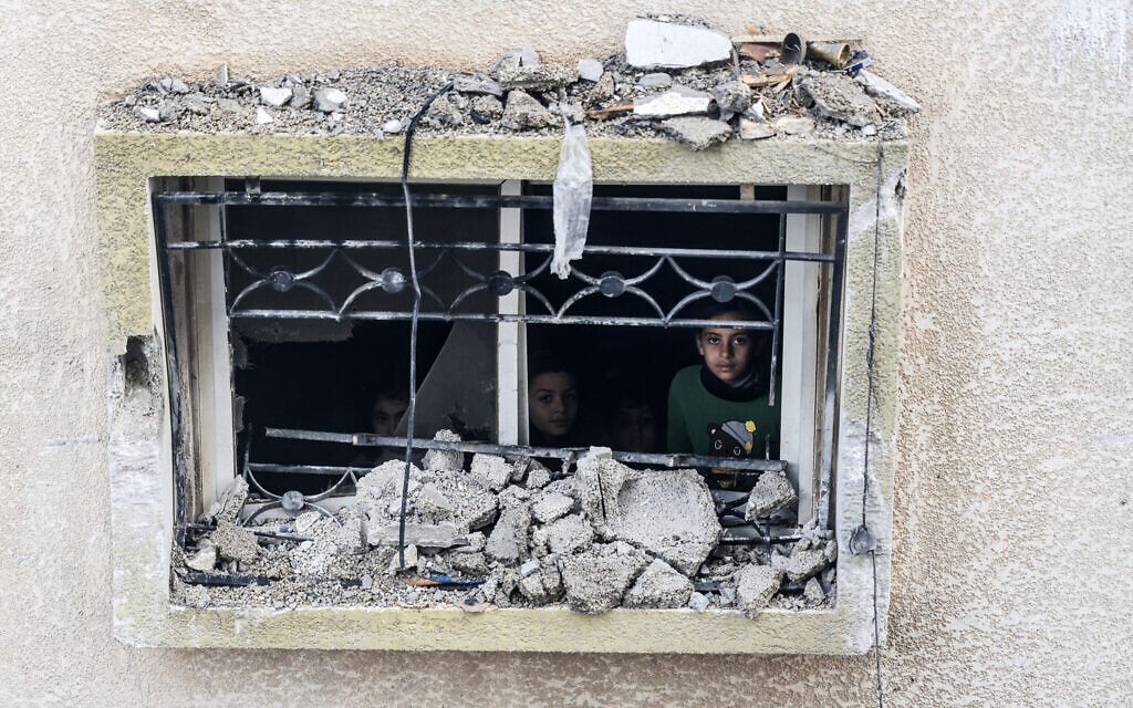 Des enfants regardent depuis la fenêtre d'un bâtiment endommagé suite à un bombardement israélien à Rafah, dans le sud de la bande de Gaza, le 9 février 2024. (Crédit : Mahmud Hams/AFP)
