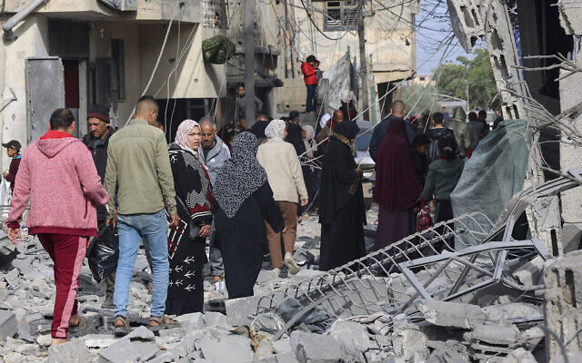 Des personnes inspectent les dégâts dans les décombres des bâtiments endommagés par les bombardements israéliens à Rafah, dans le sud de la bande de Gaza, le 12 février 2024, alors que les combats se poursuivent entre Israël et le Hamas. (Crédit : SAID KHATIB / AFP)