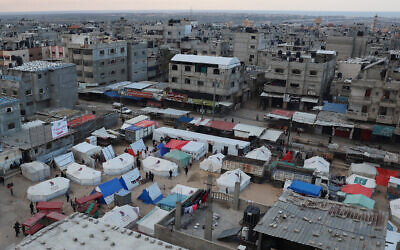 Des Palestiniens déplacés se tenant devant leurs tentes, à Rafah, dans le sud de la bande de Gaza, le 14 février 2024. (Crédit : Saïd Khatib/AFP)