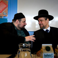 L'imam Ramazan Demir (à gauche) et le rabbin Schlomo Hofmeister s'expriment devant plus de 150 étudiants qui se pressent dans un couloir du lycée AHS Franklin à Vienne, en Autriche, le 22 février 2024. (Crédit : Joe Klamar / AFP)