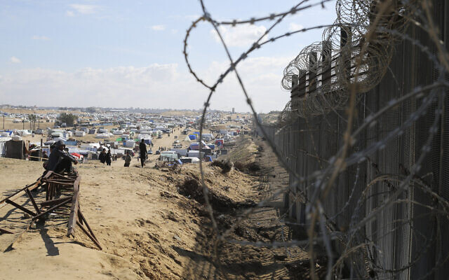 Les Palestiniens déplacés par l'offensive terrestre et aérienne dans la bande de Gaza à côté de la clôture frontalière avec l'Égypte à Rafah, le 24 janvier 2024. (Crédit : AP/Hatem Ali)