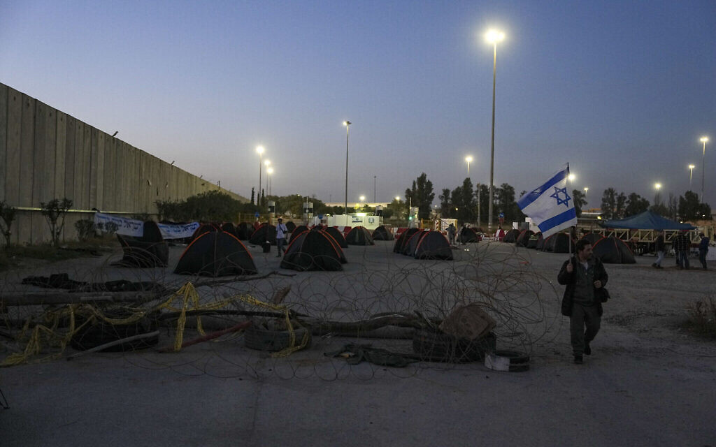 Ders activistes montent des tentes pour empêcher les camions transportant des aides humanitaires d'entrer à Gaza au poste-frontière de Kerem Shalom, entre Israël et Gaza, le 7 février 2024. (Crédit : AP Photo/Tsafrir Abayov)