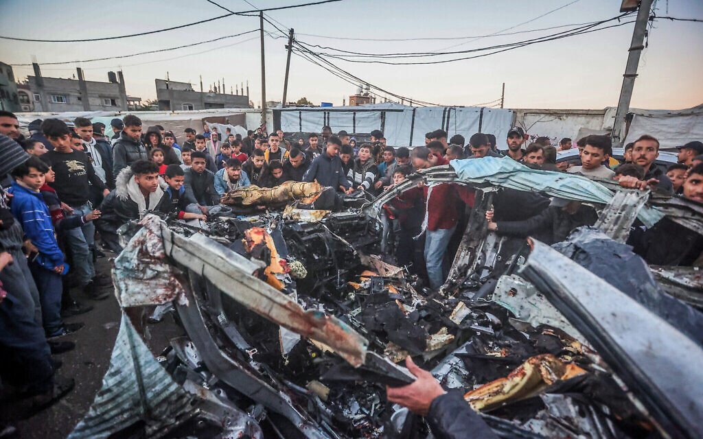 Des Palestiniens regardent une voiture de police détruite après une frappe israélienne à Rafah, dans le sud de la bande de Gaza, le 7 février 2024. (Crédit : Atia Mohammed/Flash90)
