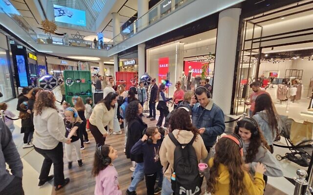 Des familles israéliennes profitant d'une fête avec casques de musique au centre commercial TLV, à Tel Aviv lors de la journée des élections municipales le 27 février 2024. (Crédit : Autorisation)