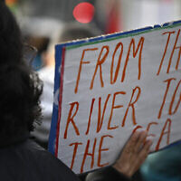Un manifestant brandit une pancarte sur laquelle on peut lire « Du fleuve à la mer » lors d'un rassemblement de solidarité avec les Palestiniens sur la place Oranienplatz, dans le quartier de Kreuzberg à Berlin, en Allemagne, le 11 novembre 2023. (Crédit : Tobias Schwarz/AFP)