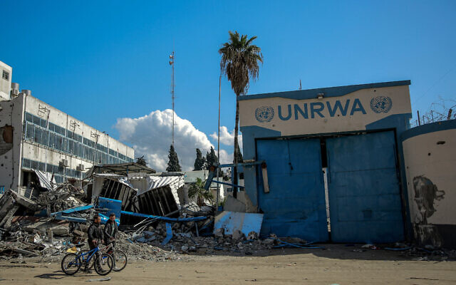Illustration : Des personnes devant le siège endommagé de l'Office controversé de secours et de travaux des Nations unies pour les réfugiés de Palestine dans le Proche-Orient (UNRWA), dans la ville de Gaza, le 15 février 2024. (Crédit : AFP)
