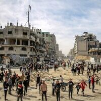 Des Palestiniens se regroupent dans la rue alors que de l'aide humanitaire est parachutée sur Gaza City, le 1er mars 2024. (Crédit : AFP)