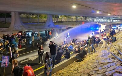 La police utilise des canons à eau contre les manifestants bloquant l'autoroute Ayalon à Tel Aviv, le 9 mars 2024. (Crédit : Adar Eyal/Israeli Pro-Democracy Protest Movement)