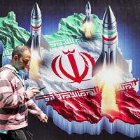 Un homme passant devant une bannière représentant des missiles lancés à partir d'une représentation de la carte de l'Iran colorée avec le drapeau iranien, dans le centre de Téhéran, le 15 avril 2024. (Crédit : Atta Kenare/AFP)