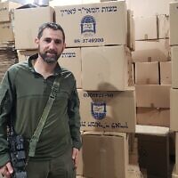 Yedidya Harush se tient à côté des boîtes de matzah fabriquées dans son usine de Netivot, le 8 avril 2024. (Crédit : Maya Zanger-Nadis/Times of Israel)