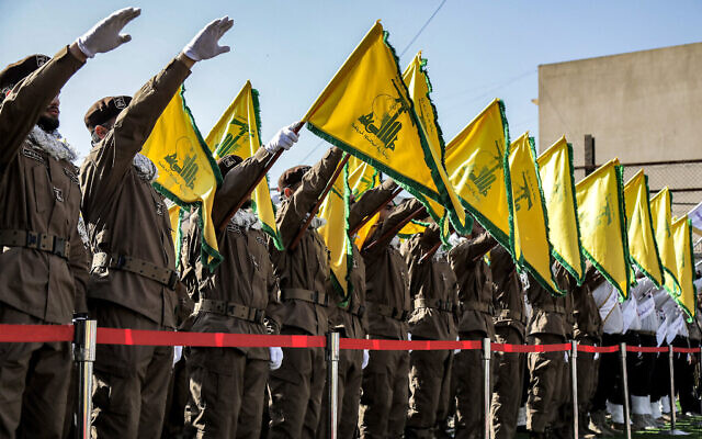 Des terroristes du Hezbollah saluant et brandissant les drapeaux jaunes du groupe lors des funérailles de combattants tués lors d'une frappe israélienne sur leurs véhicules, à Shehabiya dans le sud du Liban, le 17 avril 2024. (Crédit : AFP)