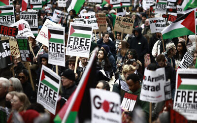 Des manifestants pro-palestiniens brandissent des pancartes et des drapeaux palestiniens pendant une marche anti-israélienne aux abords de Westminster, dans le centre de Londres, le 27 avril 2024. (Crédit : Benjamin Cremel/AFP)