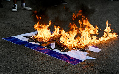Des étudiants brûlant un drapeau israélien lors d'une manifestation anti-Israël, à l'Université libanaise américaine, à Beyrouth, le 30 avril 2024. (Crédit : Joseph Eid/AFP)