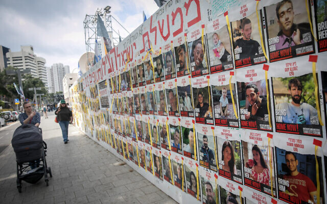 Des personnes passant devant des photographies d'Israéliens toujours retenus en otage par des terroristes du Hamas à Gaza, sur la Place des Otages, à Tel Aviv le 14 mars 2024. (Crédit : Miriam Alster/Flash90)