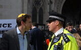 Gideon Falter, à gauche, parle à un inspecteur de police lors d'un rassemblement du groupe Campaign Against Antisemitism sur une photo non-datée, prise à Londres. (Autorisation : CAA)