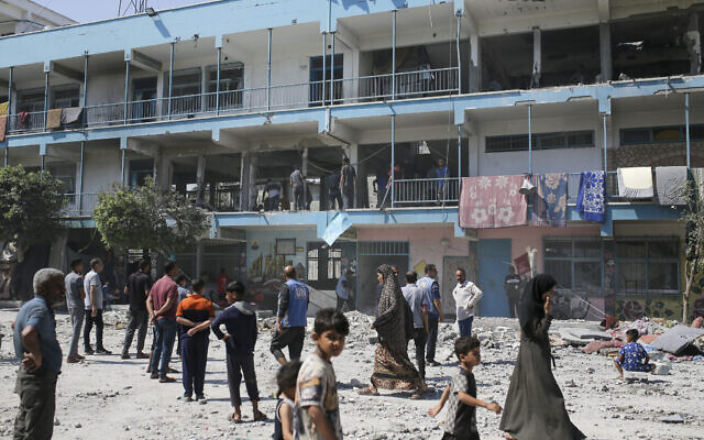 Des Palestiniens sur le site d'une école gérée par l'ONU où Tsahal affirme avoir ciblé plus de 20 terroristes menant la guerre depuis l’école, située dans le camp de réfugiés de Nusseirat, dans la bande de Gaza. (Crédit : Jehad Alshrafi/AP)