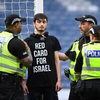 Un manifestant portant un t-shirt avec l'inscription "Carton rouge pour Israël" s'est enchaîné au poteau de but avant le match de football de qualification à l'Euro 2025 féminin entre l’Ecosse et Israël, au stade Hampden Park de Glasgow, le 31 mai 2024. (Crédit : ANDY BUCHANAN / AFP)