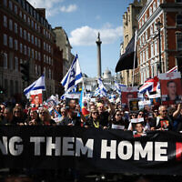 Des manifestants brandissant des pancartes et des drapeaux israéliens participent à une marche dans le centre de Londres, le 2 juin 2024, pour attirer l'attention sur le sort des otages toujours détenus à Gaza. (Crédit : HENRY NICHOLLS / AFP)