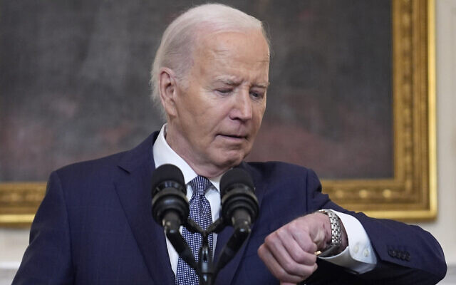 Le président américain Joer Biden regarde sa montre avant de prononcer un discours dans la salle à manger de la Maison Blanche, discours consacré au Moyen-Orient, le 31 mars 2024. (Crédit : AP Photo/Evan Vucci)