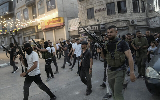 Des hommes armés brandissent leurs armes lors des funérailles de trois Palestiniens tués lors d'affrontements avec l'armée israélienne dans la ville de Jénine en Cisjordanie, le 6 juin 2024. (Crédit : AP Photo/Majdi Mohammed)