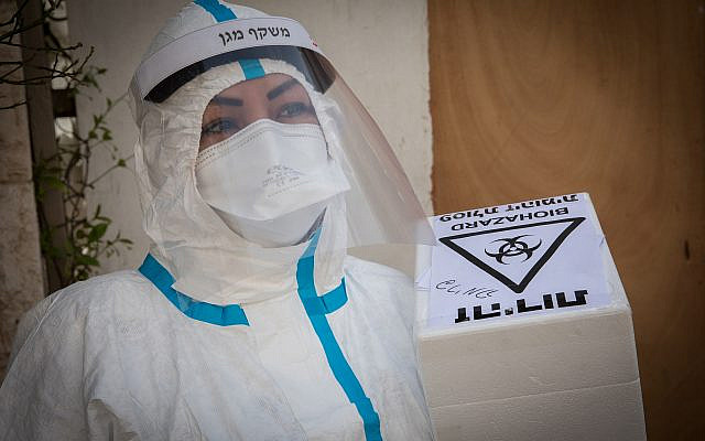 Un membre de l'équipe médicale de Magen David Adom, portant un équipement de protection, gère un test de coronavirus de patients à l'extérieur d'un hôtel utilisé comme installation de quarantaine de coronavirus, à Jérusalem le 19 avril 2020. Photo de Nati Shohat / Flash90