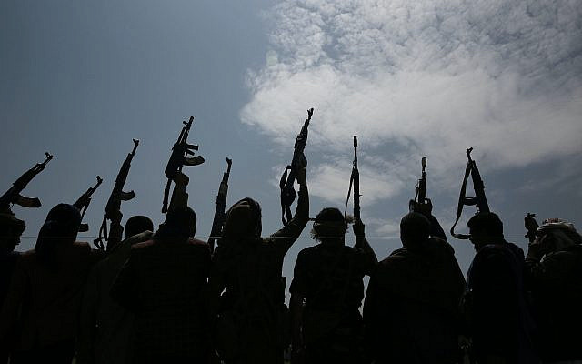 Silhouette de tribus fidèles aux rebelles Houthis levant les armes en scandant des slogans lors d'un rassemblement contre l'accord visant à établir des relations diplomatiques entre Israël et les Émirats arabes unis à Sanaa, au Yémen, le samedi 22 août 2020 (Crédit: AP Photo / Hani Mohammed)