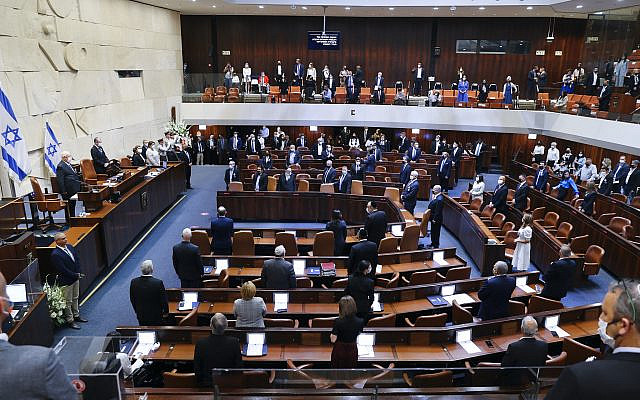 Les législateurs israéliens se tiennent dans le plénum de la Knesset lors de la cérémonie de prestation de serment du 24e gouvernement israélien, à la Knesset, ou parlement, à Jérusalem, le mardi 6 avril 2021. (Alex Kolomoisky/Piscine via AP)