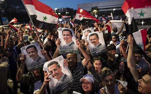 DOSSIER - Les partisans du président syrien Bashar Assad brandissant des drapeaux nationaux et des photos d'Assad alors qu'ils célèbrent sur la place Omayyad, à Damas, en Syrie, le jeudi 27 mai 2021. (AP Photo/Hassan Ammar, Dossier)