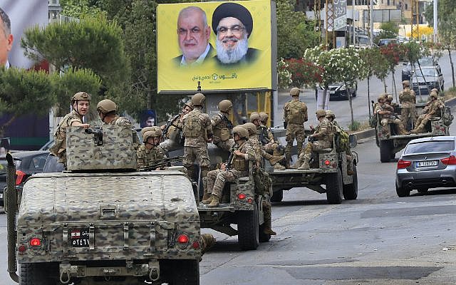 L'armée libanaise patrouillant devant une affiche montrant des portraits du chef du Hezbollah Said Hassan Nasrallah, à droite, et du chef du bloc parlementaire du Hezbollah, Mohammed Raad, à Nabatiyeh, au sud du Liban, le dimanche 15 mai 2022. AP Photo/Mohammed Zaatari)