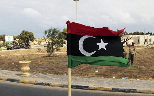 DOSSIER - Un commandant des forces révolutionnaires, Wajdi Badri, à droite, se tient à côté d'un drapeau pré-Kadhafi alors qu'il célèbre la nouvelle prise de contrôle de la place principale ouest de Syrte, en Libye, le jeudi 22 septembre 2011. (AP Photo/Gaia Anderson, File)