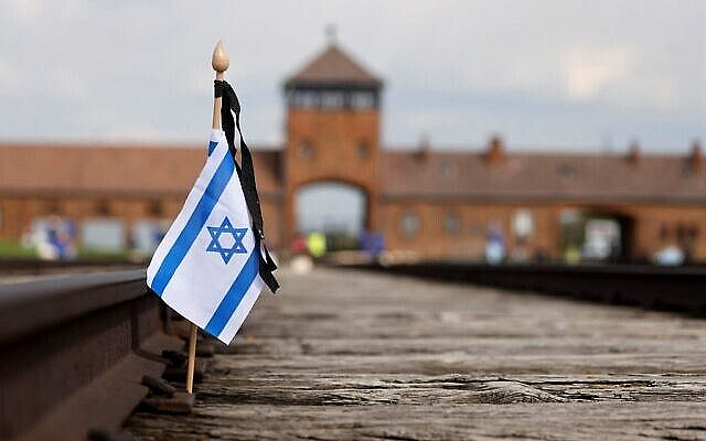 Un petit drapeau israélien sur les voies ferrées sur le site de l'ancien camp d'Auschwitz-Birkenau pendant les commémorations en l'honneur des victimes de la Shoah, près de la porte historique de Birkenau (Auschwitz II), non loin du village de Brzezinka près d'Oswiecim, en Pologne, le 28 avril 2022. (Crédit : Wojtek Radwanski/AFP)