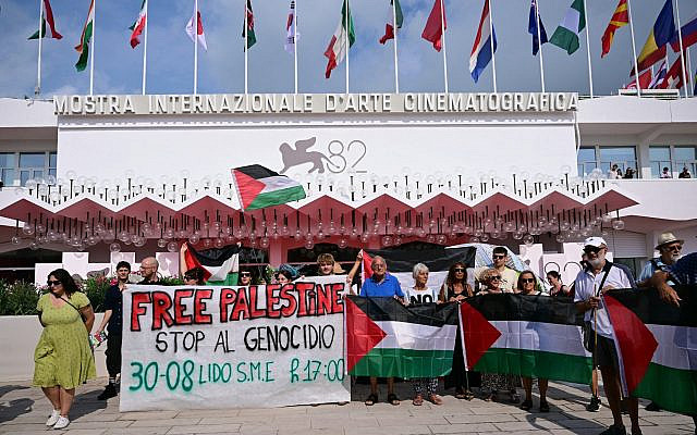 Un groupe de militants anti-Israël derrière une banderole sur laquelle on peut lire « Free Palestine - Stop Genocide » avant la cérémonie d'ouverture du 82ᵉ Festival du film de Venise, au Lido, à Venise, le 27 août 2025. (Crédit : Tiziana Fabi/AFP)
