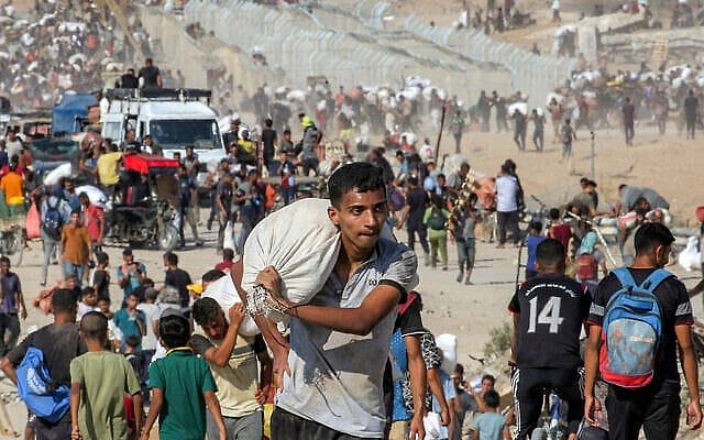 Un Gazaoui marchant avec un sacs d'aide humanitaire qui lui a été remis dans un centre de distribution géré par la Fondation humanitaire de Gaza (GHF), soutenue par les États-Unis et Israël, dans le centre de la bande de Gaza, le 22 août 2025. (Crédit : Eyad Baba/AFP)
