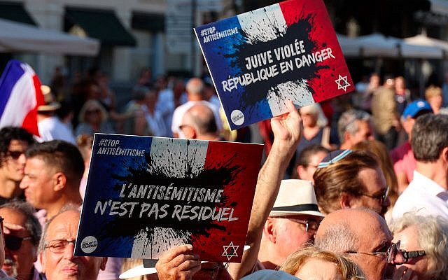 Des personnes portant des pancartes avec le logo du collectif « Nous Vivrons », où l'on peut lire « L'antisémitisme n'est pas résiduel » et « Juive violée, la République est en danger » participent à une manifestation contre l'antisémitisme à l'appel du Conseil représentatif des institutions juives de France (Crif) sur la place de la Comédie à Montpellier, le 27 août 2024, suite à l'incendie et à l'explosion de voitures qui ont visé une synagogue de La Grande-Motte, le 24 août 2024. (Crédit : Pascal GUYOT / AFP)