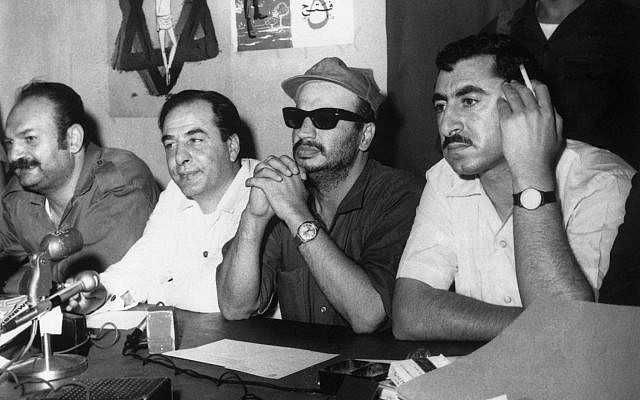 Yasser Arafat, dirigeant de  l'Organisation de libération de la Palestine (OLP), coiffé d'une casquette, photographié lors de la conférence de presse tenue à Amman, en Jordanie, le 14 juin 1970. À gauche d'Arafat se trouve Kamal Nasser, porte-parole de l'OLP, et à droite, Nayef Hawatmeh, chef du Front démocratique de libération de la Palestine (FDLP). (Crédit : AP)