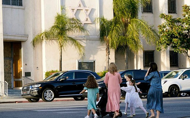 Mères et filles se dirigent vers la synagogue Shaarei Tefila de la Congrégation de Los Angeles à l’occasion de la fête juive de Simchat Torah, le 7 octobre 2023. (Crédit : Damian Dovarganes/AP)
