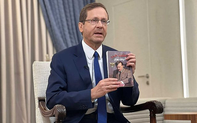 Le président Isaac Herzog montrant un exemplaire d'une traduction arabe de "Mein Kampf" qui a été trouvée par les soldats israéliens dans une chambre d'enfant utilisée comme base terroriste dans la bande de Gaza, à la résidence présidentielle, le 12 novembre 2023. (Crédit : Bureau du président)