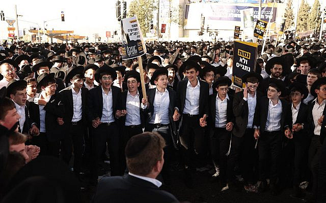 Des Juifs ultra-orthodoxes brandissent des pancartes et dansent pour protester contre la conscription dans l'armée israélienne, à Jérusalem, le 30 octobre 2025. (Crédit : Fadel SENNA / AFP)