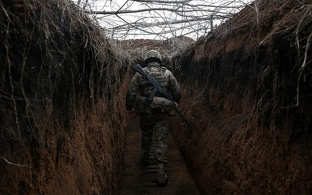 Un soldat ukrainien marche le long d’une tranchée sur la ligne de front avec des séparatistes soutenus par la Russie près de Novolugansk dans la région de Donetsk en Ukraine, le 16 février 2022. Sur la ligne de front ukrainienne : là où les cessez-le-feu théoriques deviennent des questions de survie. (Crédit : Anatolii Stepanov/AFP)