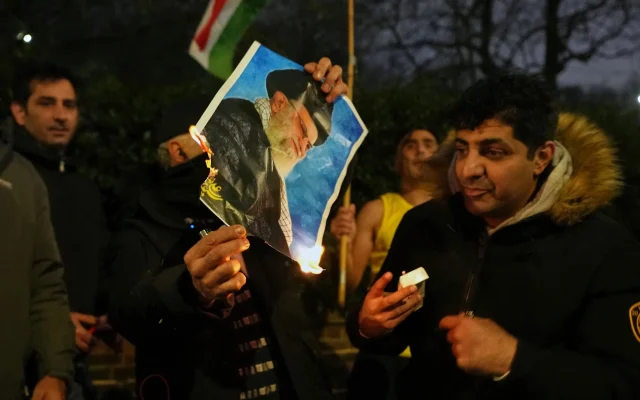 Une photo de l'ayatollah Ali Khamenei brulée par des manifestants devant l'ambassade d'Iran, à Londres, le 12 janvier 2026. (Crédit : Alastair Grant/AP)
