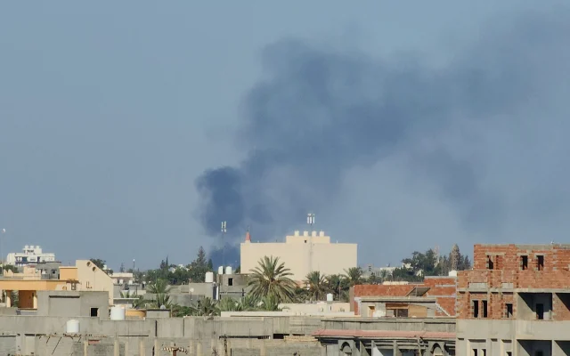 Des panaches de fumée s'élèvent au milieu d'affrontements entre groupes armés affiliés au Gouvernement d'union nationale (GNU) basé à Tripoli, en Libye, le 15 août 2023. (Crédit : Mahmud Turkia/AFP)