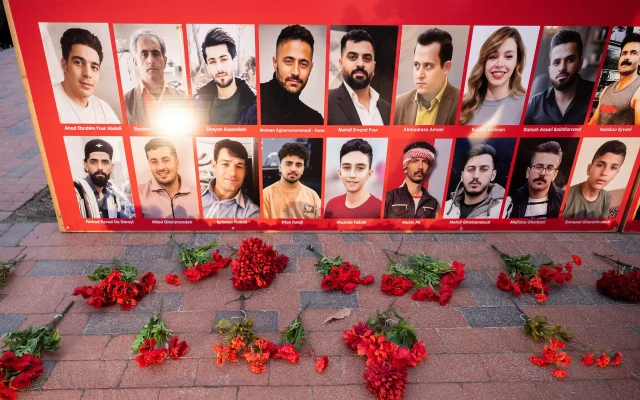 Des fleurs sont déposées à côté d'un panneau présentant des photos de personnes iraniennes tuées lors des récentes manifestations en Iran, lors d'une veillée organisée en leur honneur par des Américains d'origine iranienne, devant la Maison Blanche à Washington, le 16 janvier 2026. (Crédit : Saul Loeb/AFP)