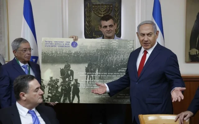 Le Premier ministre israélien Benjamin Netanyahu (d) reçoit un cadeau de l'Institut Zeev Jabotinsky lors de la réunion hebdomadaire du cabinet à Jérusalem, le 8 juillet 2018. (Crédit : AFP/POOL/ABIR SULTAN)