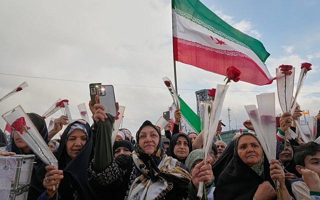 Des personnes brandissent des roses lors d'une cérémonie de mariage collectif à Téhéran, en Iran, le 18 mai 2026. (Crédit : AP/Vahid Salemi)