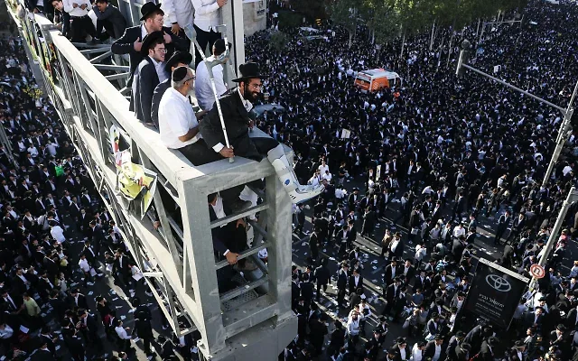 Des hommes ultra-orthodoxes sont assis sur un pont surplombant la foule, lors d’une manifestation de juifs ultra-orthodoxes contre la conscription dans l’armée israélienne, à Jérusalem, le 30 octobre 2025. (Crédit : AHMAD GHARABLI / AFP)