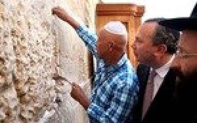 Hip-hop mogul Russell Simmons places a note in the Western Wall during his recent trip to Israel. Behind Simmons is his partner for Muslim-Jewish dialogue work, Rabbi Marc Schneier. (Credit: Sasson Tiram)
