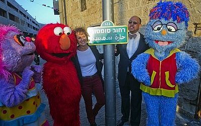 Avigail, Elmo, Alona Abt ("Rehov Sumsum's" director on its set in Herzliya), Melvin Ming (president and CEO of Sesame Workshop), and the Arab-Israeli character Mahboub. In the center is the "Rehov Sumsm" ("Sesame Street") sign. (Credit: D Guthrie)