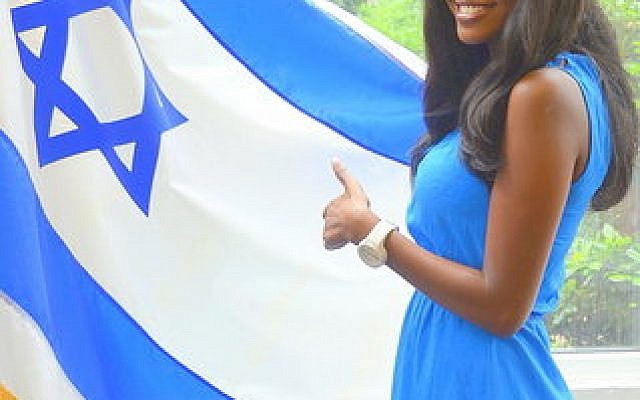 Yitayish Ayenew, the first black Miss Israel and also the first woman of Ethiopian heritage to win the crown, poses with the Israeli flag at Solomon Schechter Day School of Bergen County, N.J., Friday, June 14. (Maxine Dovere photo)