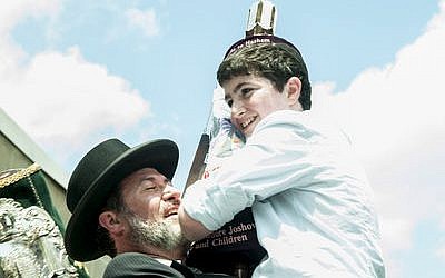 Rabbi Daniel Wasserman raises his son Moshe to dance and celebrate with a new Sefer Torah at Hillel Academy in 2013. The Sefer Torah was dedicated by the Joshowitz family. (Photo by Lindsay Dill)
